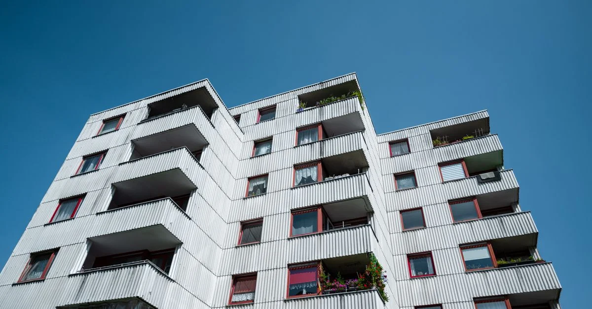 Vue rapprochée de la façade d'un immeuble d'appartements moderne contre un ciel bleu clair.