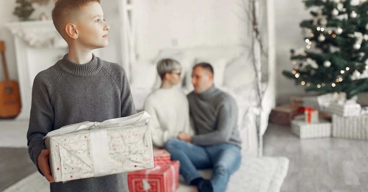 Un garçon tenant un cadeau dans un cadre familial chaleureux de Noël avec un sapin.